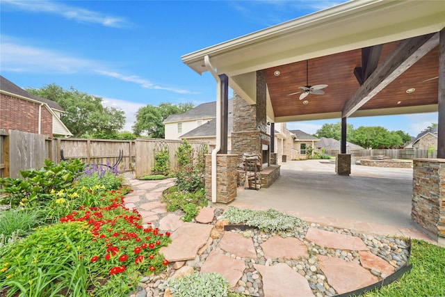 view of patio / terrace with an outdoor stone fireplace, a fenced backyard, and ceiling fan
