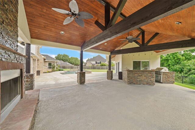 view of patio with an outdoor stone fireplace, a ceiling fan, fence, and area for grilling