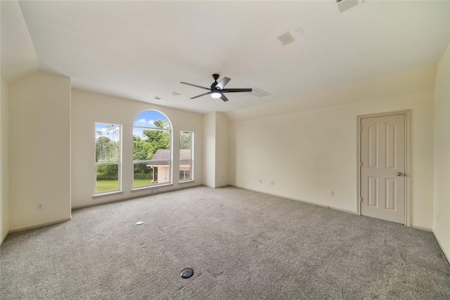 carpeted empty room featuring visible vents, a ceiling fan, and baseboards