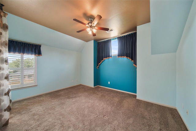 carpeted empty room featuring visible vents, baseboards, ceiling fan, and lofted ceiling