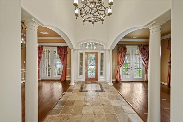 entrance foyer featuring a healthy amount of sunlight, arched walkways, french doors, and a chandelier