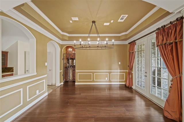 unfurnished dining area featuring visible vents, ornamental molding, an inviting chandelier, a raised ceiling, and french doors