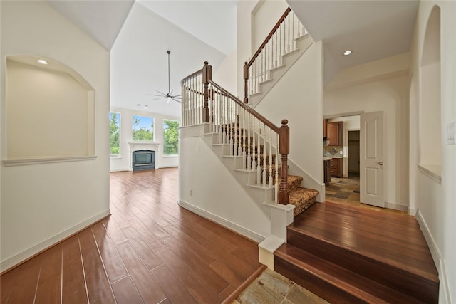 staircase with baseboards, ceiling fan, wood finished floors, and a fireplace