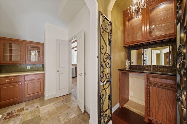 interior space featuring baseboards, decorative backsplash, arched walkways, and a notable chandelier