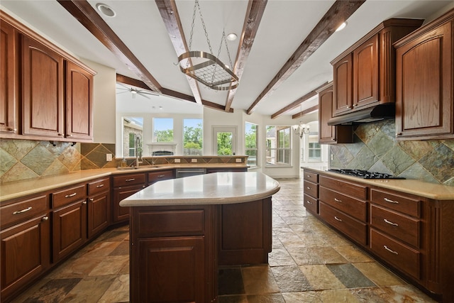 kitchen featuring a sink, beamed ceiling, a ceiling fan, and stone tile floors