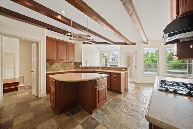 kitchen with backsplash, beam ceiling, light countertops, extractor fan, and stone tile floors
