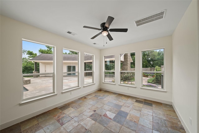 unfurnished sunroom with plenty of natural light, stone tile floors, and visible vents