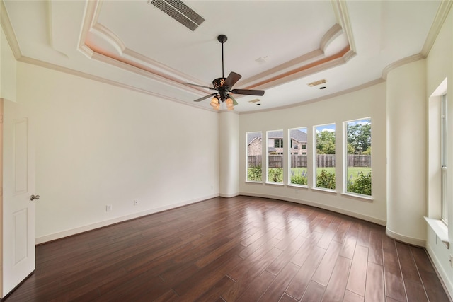 unfurnished room with ceiling fan, visible vents, a raised ceiling, ornamental molding, and dark wood-type flooring