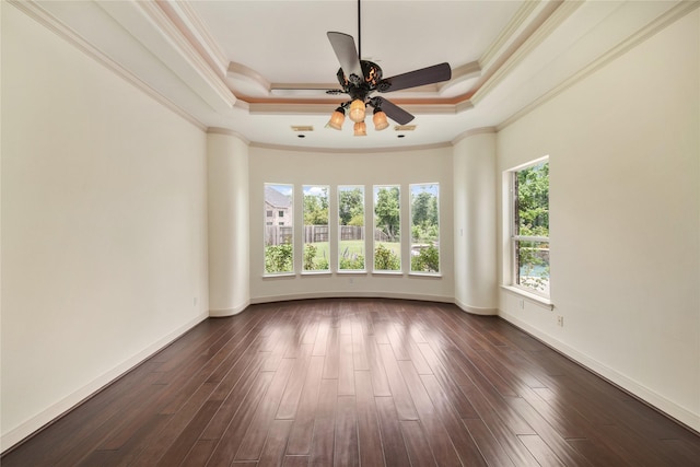 empty room featuring a tray ceiling, crown molding, a ceiling fan, and dark wood finished floors
