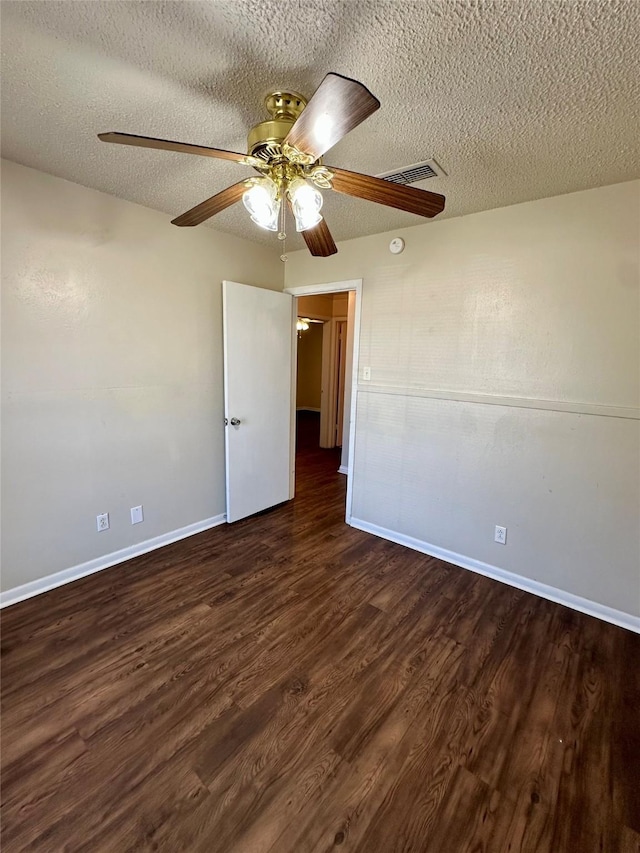 unfurnished room with a textured ceiling, visible vents, ceiling fan, baseboards, and dark wood finished floors