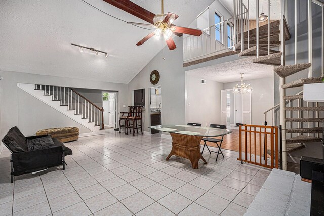 13126 Birch Grove Dr, Houston, TX 77099 - dining space with stairs, ceiling fan with notable chandelier, high vaulted ceiling, a textured ceiling, and light tile patterned flooring
