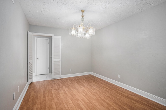13126 Birch Grove Dr, Houston, TX 77099 - unfurnished room featuring baseboards, a notable chandelier, a textured ceiling, and light wood finished floors