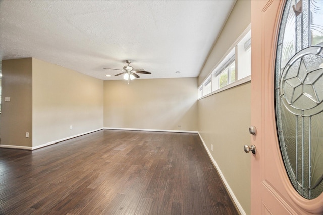 foyer featuring a ceiling fan, baseboards, a textured ceiling, and dark wood-type flooring