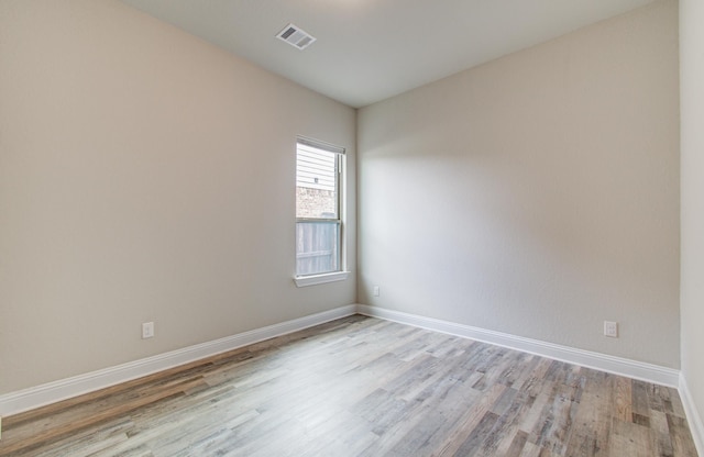 spare room featuring baseboards, visible vents, and light wood-style flooring