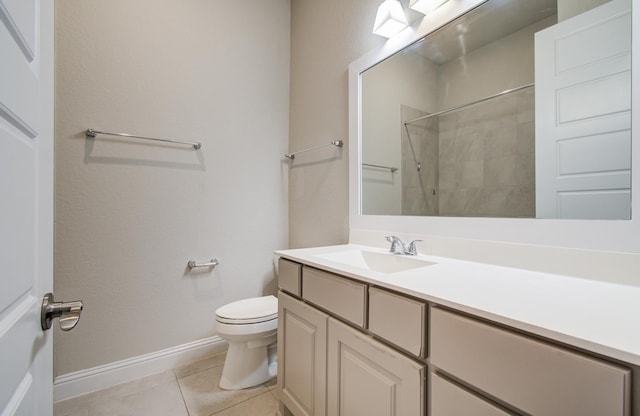bathroom featuring tile patterned flooring, toilet, vanity, baseboards, and a shower
