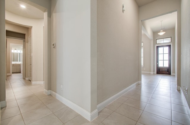 corridor featuring light tile patterned flooring and baseboards