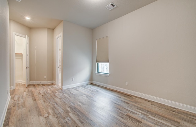 unfurnished room featuring baseboards, visible vents, light wood-style flooring, and recessed lighting