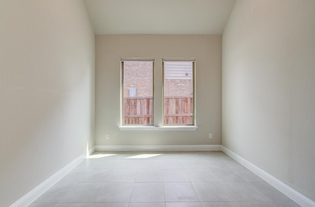 empty room with light tile patterned floors and baseboards