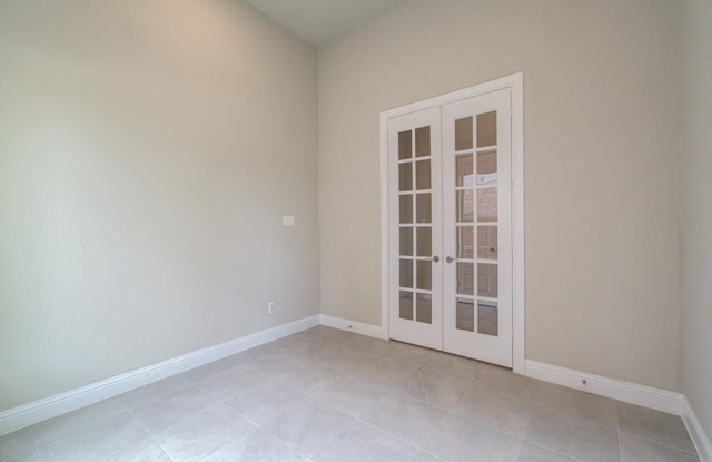 spare room featuring light tile patterned floors, french doors, and baseboards