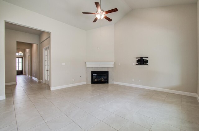 unfurnished living room featuring baseboards, light tile patterned flooring, a tiled fireplace, a ceiling fan, and high vaulted ceiling