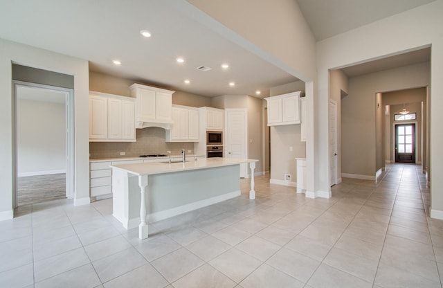 kitchen with appliances with stainless steel finishes, light countertops, backsplash, a sink, and light tile patterned flooring