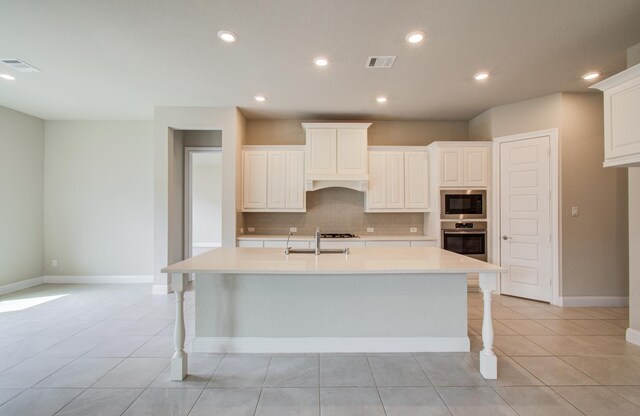 kitchen with tasteful backsplash, visible vents, light countertops, built in microwave, and stainless steel oven