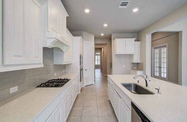 kitchen with tasteful backsplash, appliances with stainless steel finishes, white cabinets, a sink, and visible vents