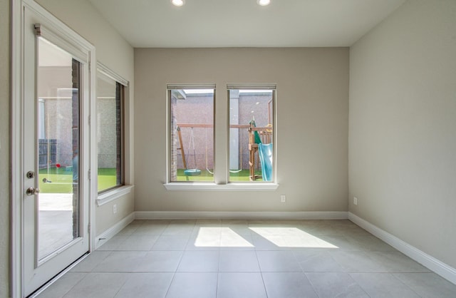spare room featuring light tile patterned floors, a healthy amount of sunlight, recessed lighting, and baseboards