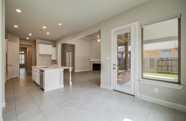 kitchen featuring a fireplace, a sink, white cabinetry, visible vents, and open floor plan