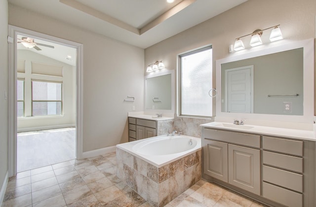bathroom featuring two vanities, ceiling fan, a bath, and a sink