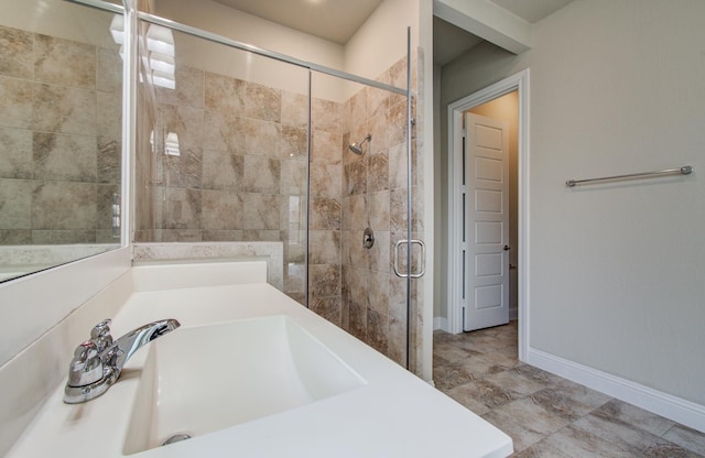 full bath featuring baseboards, a stall shower, and a sink