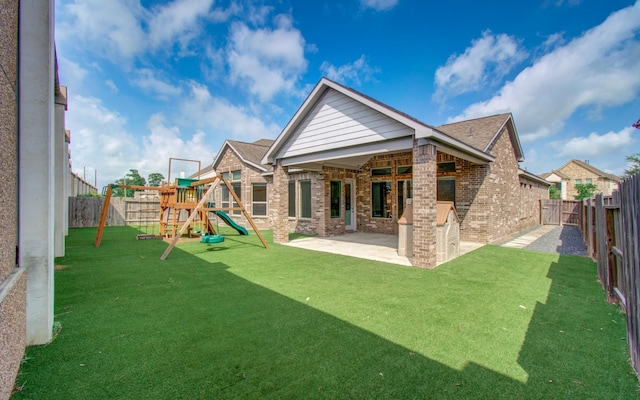 back of property with a patio, a fenced backyard, a lawn, a playground, and brick siding