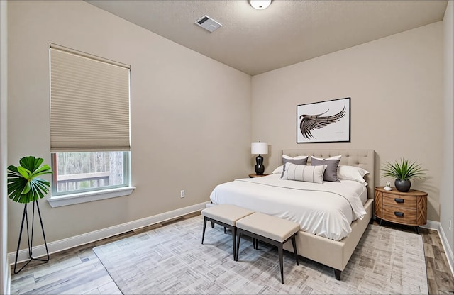 bedroom with visible vents, wood finished floors, and baseboards
