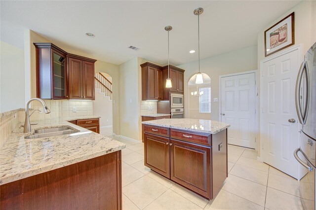 kitchen with a sink, appliances with stainless steel finishes, decorative backsplash, arched walkways, and light tile patterned floors