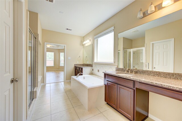 full bath featuring a shower stall, a garden tub, tile patterned floors, two vanities, and baseboards