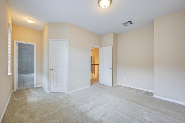 unfurnished bedroom with carpet, ensuite bath, and baseboards