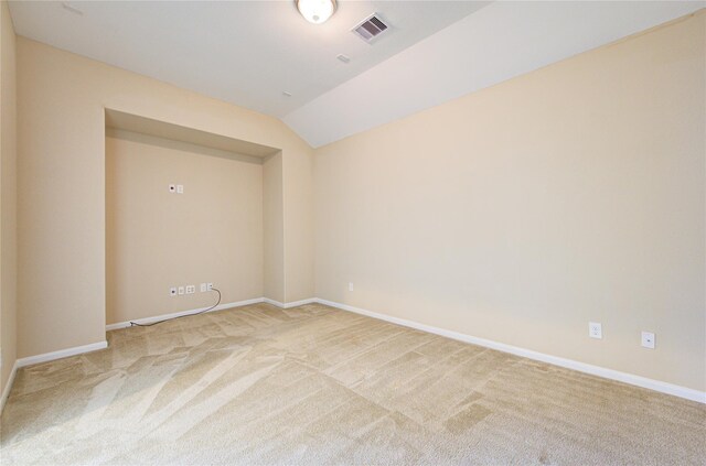 spare room featuring light carpet, baseboards, and lofted ceiling