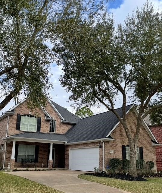 1615 Lakeside Enclave Dr, Houston, TX 77077 - view of front of home with brick siding, a garage, driveway, and roof with shingles