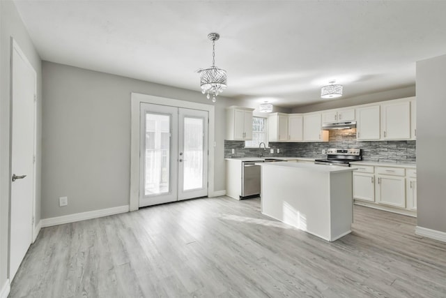 kitchen with tasteful backsplash, appliances with stainless steel finishes, light countertops, under cabinet range hood, and light wood finished floors