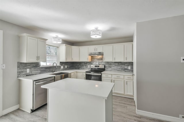 kitchen with baseboards, appliances with stainless steel finishes, under cabinet range hood, and tasteful backsplash