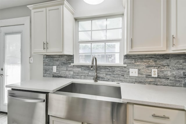 kitchen with white cabinetry, stainless steel dishwasher, decorative backsplash, and a sink