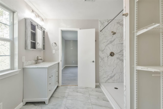 bathroom with a marble finish shower, marble finish floor, visible vents, and vanity