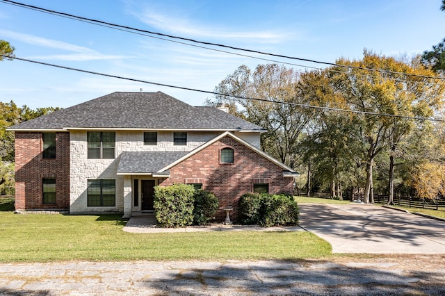 traditional home featuring a front yard, a shingled roof, concrete driveway, and brick siding