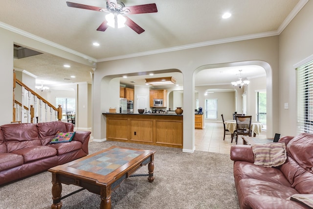 living room with crown molding, arched walkways, light carpet, and ceiling fan with notable chandelier