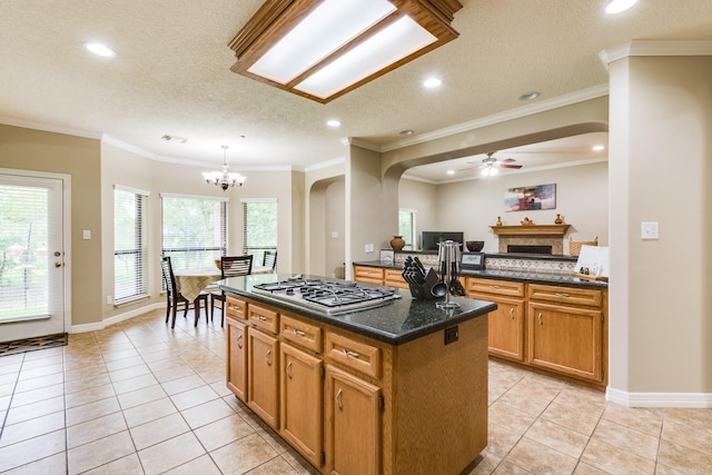 kitchen featuring a center island, stainless steel gas cooktop, arched walkways, and a fireplace