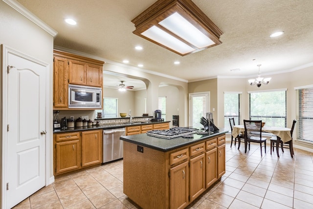 kitchen featuring light tile patterned floors, stainless steel appliances, dark countertops, and a sink