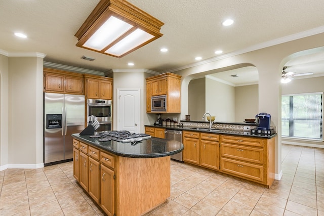 kitchen featuring arched walkways, stainless steel appliances, a center island, a sink, and visible vents