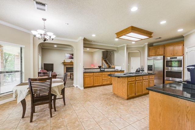 kitchen with a fireplace, stainless steel appliances, a notable chandelier, and arched walkways