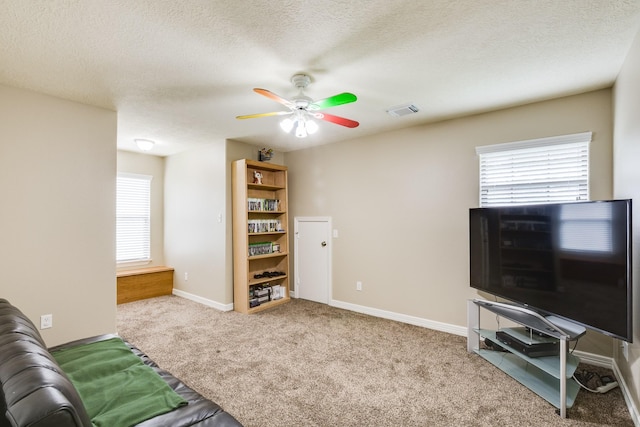 carpeted living room with a textured ceiling, visible vents, a ceiling fan, and baseboards