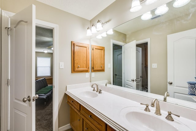 ensuite bathroom with double vanity, baseboards, ensuite bath, and a sink